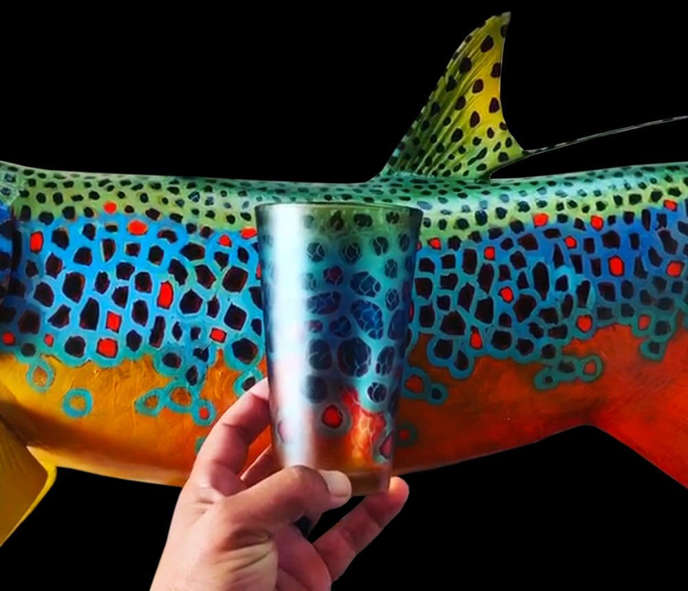 Derek DeYoung Brown Trout Flank pilsner glass held in front of trout artwork
